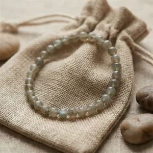 Pulsera de labradorita con destellos grises y verdes sobre bolsa de yute natural